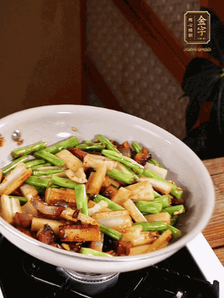 油熱下蒜末、干辣椒、醬肉煸炒出香味，依次下藕條、豆角翻炒均勻